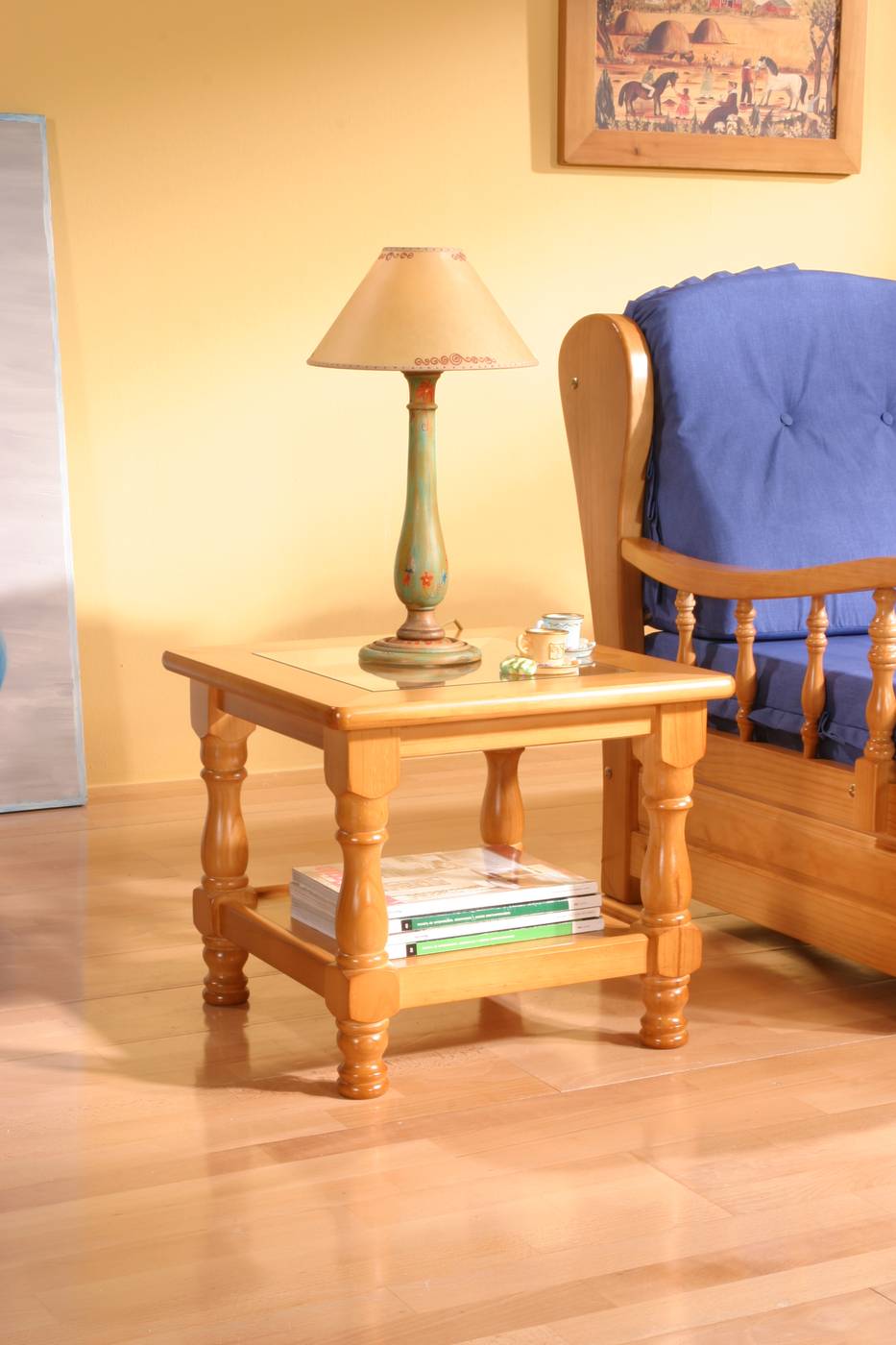 Mesa de rincón cuadrada con revistero y tapa de cristal. Fabricada de madera de pino maciza. Disponible en varios colores